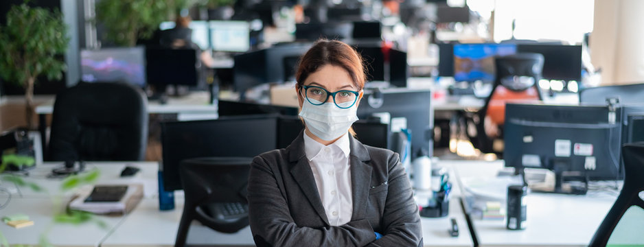 Business Woman In Office In A Protective Mask And Gloves. Female Manager With Glasses And A Suit Works In An Epidemic Of Coronavirus. Caring For The Health And Safety Of Staff. Mask Mode.