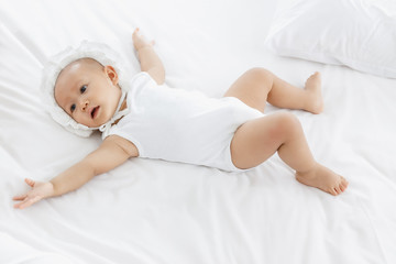 Baby girl laying on white bedroom.