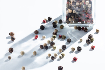 mix of allspice is sprinkled from a glass jar on white.