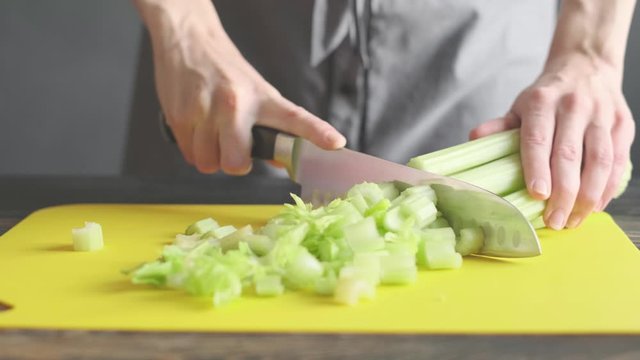 a woman prepares slices on a cutting board ingredients for a celery smoothie and puts them in a blender bowl