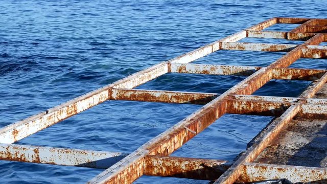 Old painted rusted iron beams on the seashore in the water