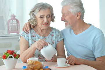 Portrait of mature couple drinking tea with cookies