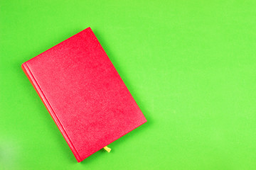 Top view of a red Notepad and , on a green background. Concept of time and planning. Time to fill out your gratitude diary in the morning. Copy space.