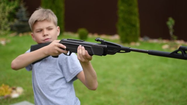 boy child from a shotgun is aiming at target of outdoor. boy learns to shoot.