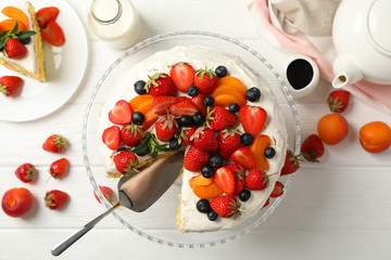Composition with delicious berry cream cake on white wooden table. Tasty dessert