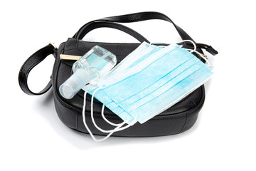 covid-10 protective fashion, hand sanitizer and surgical masks on a ladies purse