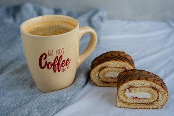 Two slices of sponge roll and a cup of coffee with text on textile table at kitchen