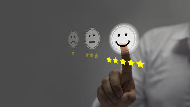 Businessman pressing smiley face emoticon on virtual touch screen. Customer service evaluation concept.	
