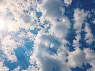 White beautiful cumulus clouds on a blue sky lit by the sun.
