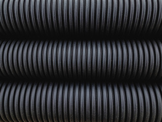 Black plastic corrugated pipes in natural light. Background image.