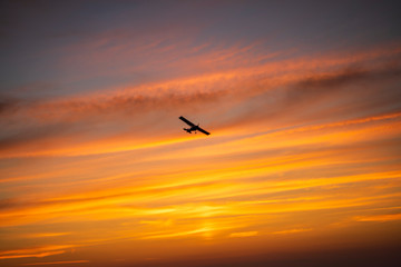 The plane flies across the sunset sky in the evening, bright orange colors, stripes.