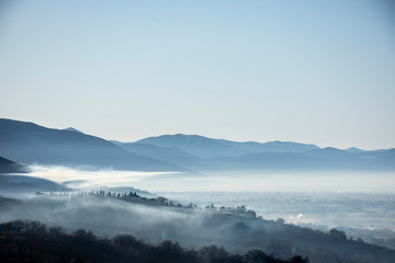 Pueblo ubicado en las colinas durante amanecer de día con niebla