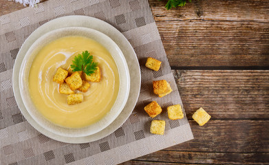 Fresh butternut squash creamy chicken soup in gray bowl garnished with crispy croutons .