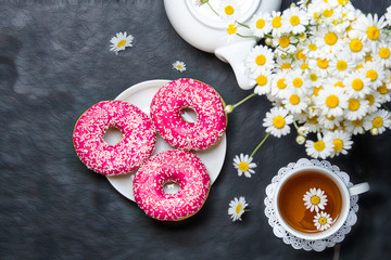 A cup of tea and fresh delicious donuts and a bouquet of field daisies.Flat lay.