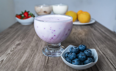 plain blueberry yogurt in a glass bowl with fresh fruit on a plate
