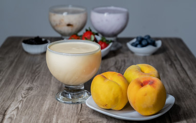 natural peach yogurt in a glass bowl with fresh fruit on a plate
