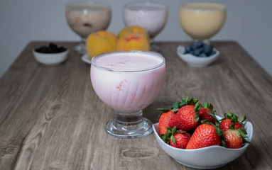 natural strawberry yogurt in a glass bowl with fresh fruit on a plate
