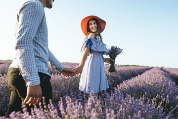 Fototapeta premium Beautiful young couple embracing and walking together outdoor in lavender field.