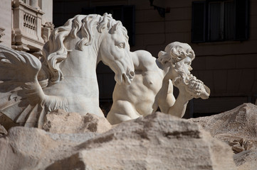 Detail of a triton and seahorse dramatically lit against a dark background on the Trevi Fountain in Rome, one of the famous fountains of Rome and a major tourist attraction in the city.