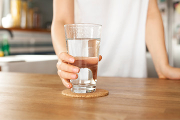 Young woman holds a glass of water. clean drinking water in a clear glass in your hands close-up.