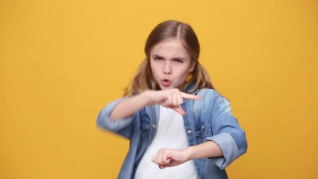 Little fun blonde kid teen teenager girl 12-13 years old in denim jacket white t-shirt posing isolated on yellow background studio People childhood lifestyle concept Dancing waving hand fooling around