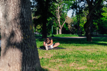 Healthy young man doing outdoors warmup stretching exercises on a fitness mat