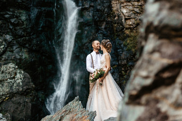 Fototapeta na wymiar Bride and Groom standing near the waterfall