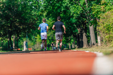 Obraz premium Rearview of two male friends running outdoors in a park