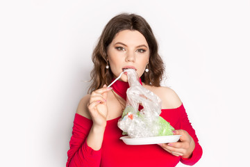Young beautiful woman eating a plastic bag as a concept of plastic contaminated food. Ecology...