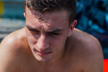 Closeup face portrait of a tired and sweaty male athlete resting after training