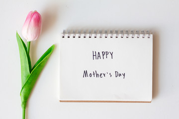 Write text happy mother's day on paper notebook with tulips flowers on white background.