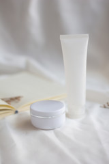 Fototapeta na wymiar White jar of cream on white fabric background. beauty and cosmetic product, mock up,