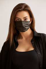Young woman wearing medical face mask, studio portrait