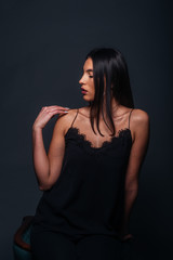 Naklejka premium Beautiful sexy woman with straight black hair looking aside and being isolated on a dark background
