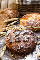 Concept of homemade bread, natural farm products, domestic production. Healthy and tasty organic food. Wheat spica as decor. Closeup, macro, wooden background