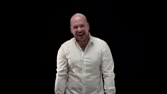Bald bearded man in white shirt laughs at camera, shows his fingers. A businessman in crumpled shirt is crazy and pokes fingers at someone. Isolate black background.