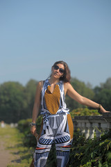 woman in the summer in the park in sunglasses and summer overalls