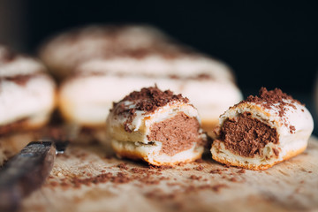 Cake eclairs in white chocolate with chocolate brown crumb in a cut. Close-up. Traditional French dessert. Fast carbohydrates. High sugar content.