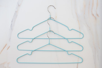 Flat lay set of blue hangers on white marble. Many colored hangers lying chaotically, minimal concept