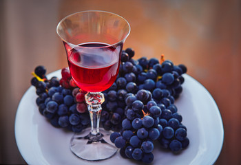 a glass of red wine on the background of grape