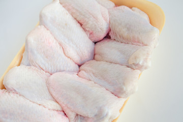 Fresh chicken wings in a plate on a white marble table with copy space. Raw chicken wings on a white background