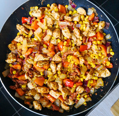 Making chicken quesadillas at home. Pan on the hob with chicken, onions, corn and red peppers....