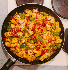Making jambalaya dish at home. Pan on the hob with rice, chicken, chorizo, prawns and green...