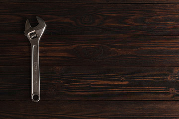 .Steel wrench on a wooden brown background. Metal wrench top view.