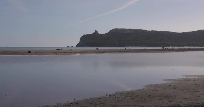 nearly empty beach with calm water and mountains on Sardinia Italy colorless movie