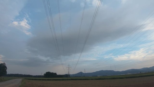 Electric line tower on farming fields in Slovenia. Wide shot, tilt up