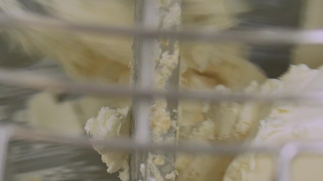 Close up of butter and icing being mixed up to create a topping for cakes. large mechanical whisk brings ingredients together