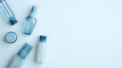 Set of natural organic SPA cosmetic products on blue background. Flat lay, top view transparent cosmetic bottles and cream jar. Banner mockup for beauty salon.