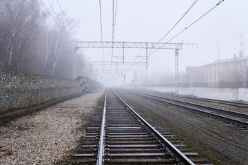 Fototapeta premium railroad rails lurking in fog in perspective