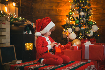 Obraz na płótnie Canvas Little Santa Claus helper elf with a magic gift for Christmas. Christmas. Santa little helper. Happy family concept. Little genius. Little boy in Santa hat and costume having fun. New Year.